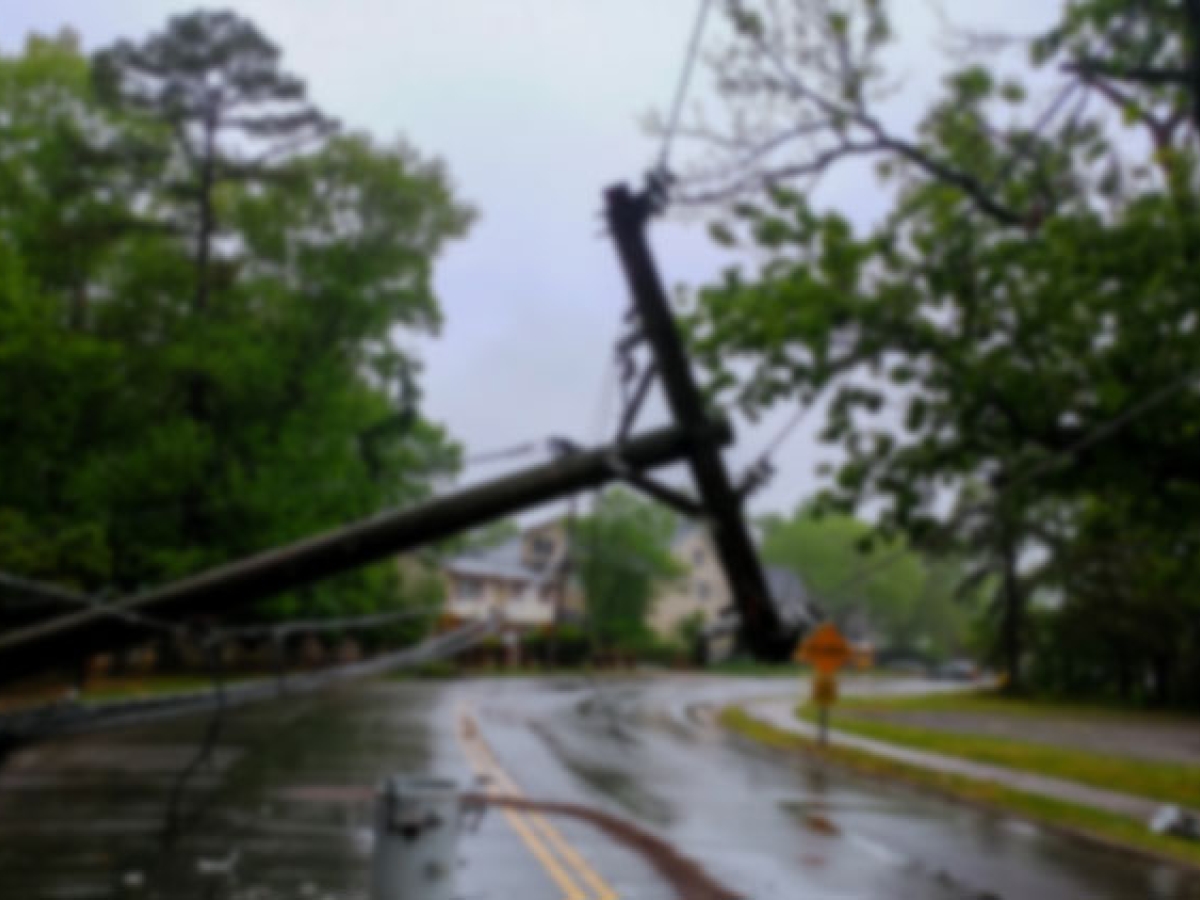 Electricity pole that has fallen down and is laying in the street.